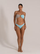 Front-facing view of model in grey and blue colorblock bandeau bikini with high-cut bottoms.