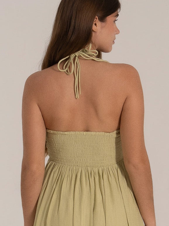 Woman wearing light olive halter maxi dress with smocked back, viewed from behind