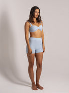 Side-front view of a woman wearing a ribbed light blue bikini top and matching high-waisted shorts