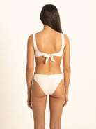 Rear straight-on view focusing on the elegant tie-back knot closure of the Ivory ribbed bikini top, paired with moderate coverage cheeky bottoms.