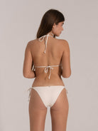 Back view of woman wearing an ivory halter tie string bikini with minimal coverage.