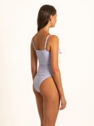 Low-angle back profile of the lavender floral eyelet tankini set on a model, highlighting the cheeky thong-style coverage.