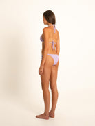 Female model turned halfway back in lilac textured bikini with halter and back tie