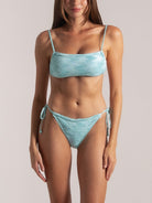 Front view of a woman in a light blue bandeau bikini set with spaghetti straps and ruched texture