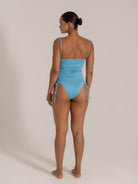Back view of a light blue ruched one-piece swimsuit with side ties and adjustable straps.