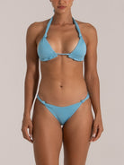Woman wearing light blue shimmer triangle bikini with knot details, front view.