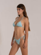 Woman in light blue halter bikini with triangle cups and tie sides, turned slightly to the side.