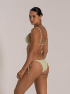 Woman wearing a light green ribbed triangle bikini with adjustable shoulder straps, back view.