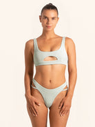 Front view of light green bikini top with cut-out design and textured fabric.