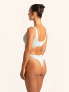 Light green bikini top in textured fabric with modern cut-out front detail.