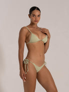 Side angle view of a model in a light green textured bikini set with triangle top and tie-side bottoms.