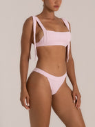 Model posing in light pink textured bikini bottom with high-cut leg and textured finish