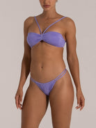Model in a sparkly light purple bikini set with V-strap bandeau top and double-strap thong bottom, angled front pose