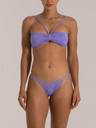 Woman wearing a light purple bikini with double side strap bottom and ruched bandeau top with V cross-strap detail, front view