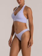 Side angle of a model in a lavender halter bikini with wide straps and sculpted bust support.