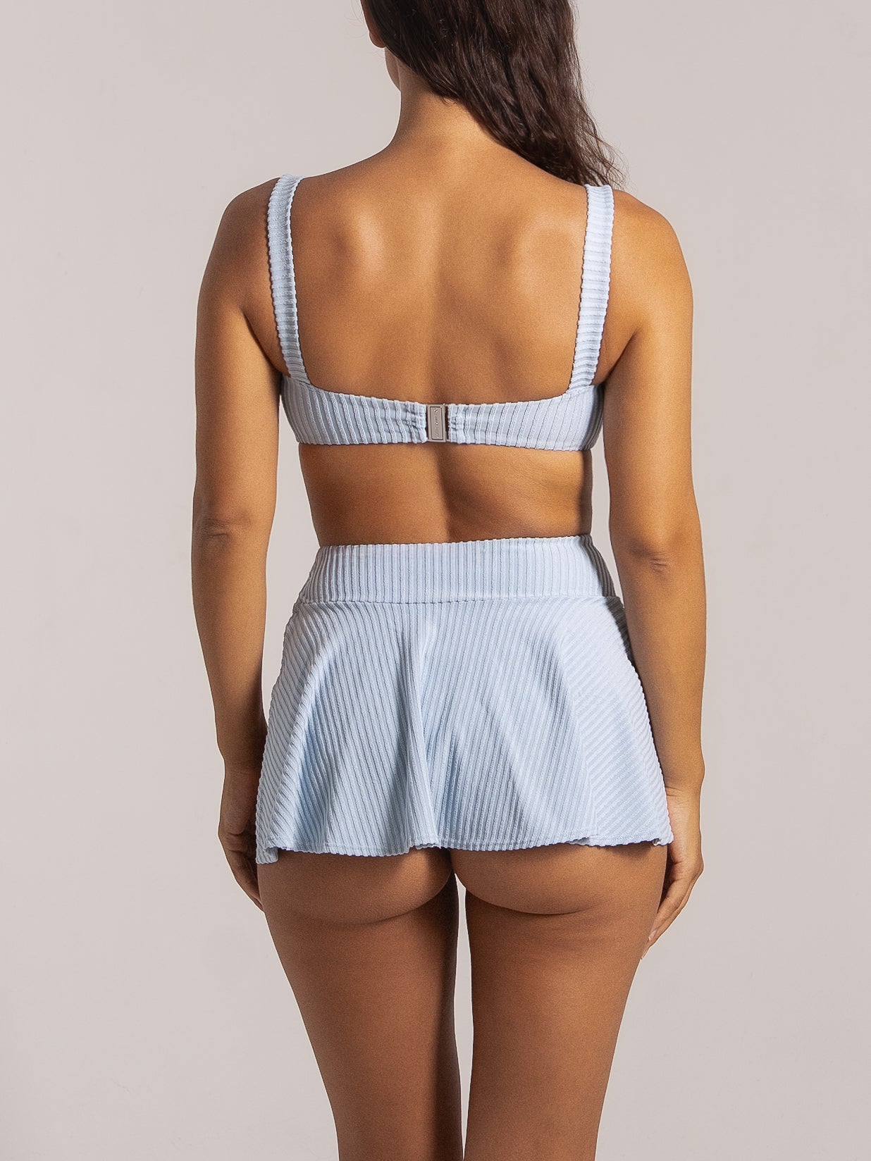 Full back view of light blue pleated swim skirt over bikini bottoms.