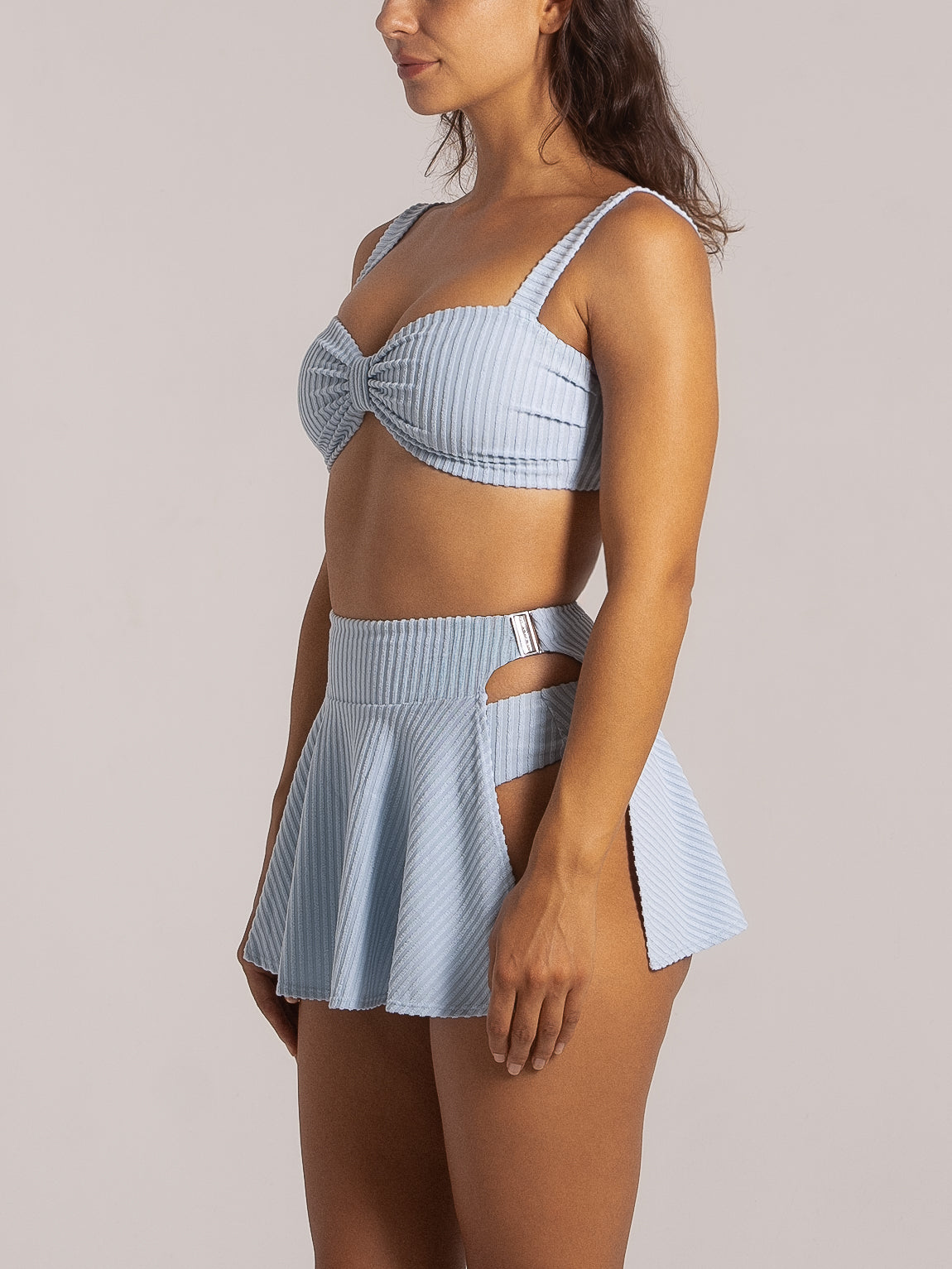 Side view of pleated light blue swim skirt showing double side cutouts and textured fabric.