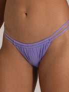 Detailed close-up of lilac thong bikini bottom with ruched front and shimmer texture