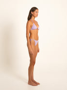 Side profile of model wearing lilac string bikini with textured fabric and tie details