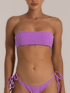 Front view of a woman wearing a lilac textured bandeau bikini top paired with tie-side bikini bottoms, featuring a soft zebra-inspired pattern and minimal strap design.