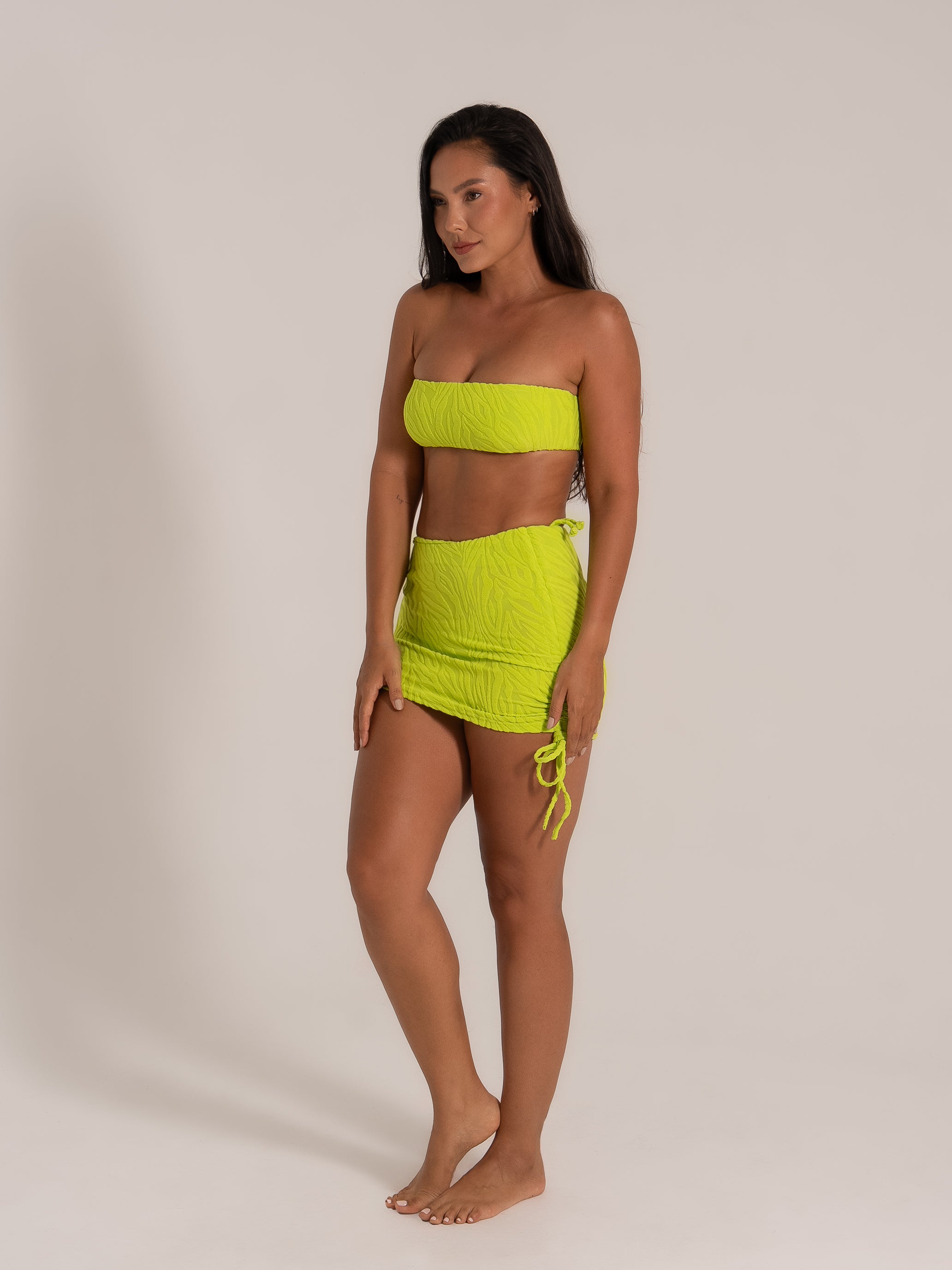Side view of model wearing bright lime green bikini skirt set, ideal for a vibrant beach look.