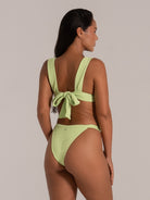 Rear view of a lime green bikini top featuring thick shoulder straps and a statement bow tie.