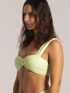 Side angle of a lime green bikini top with bow center detail and textured fabric