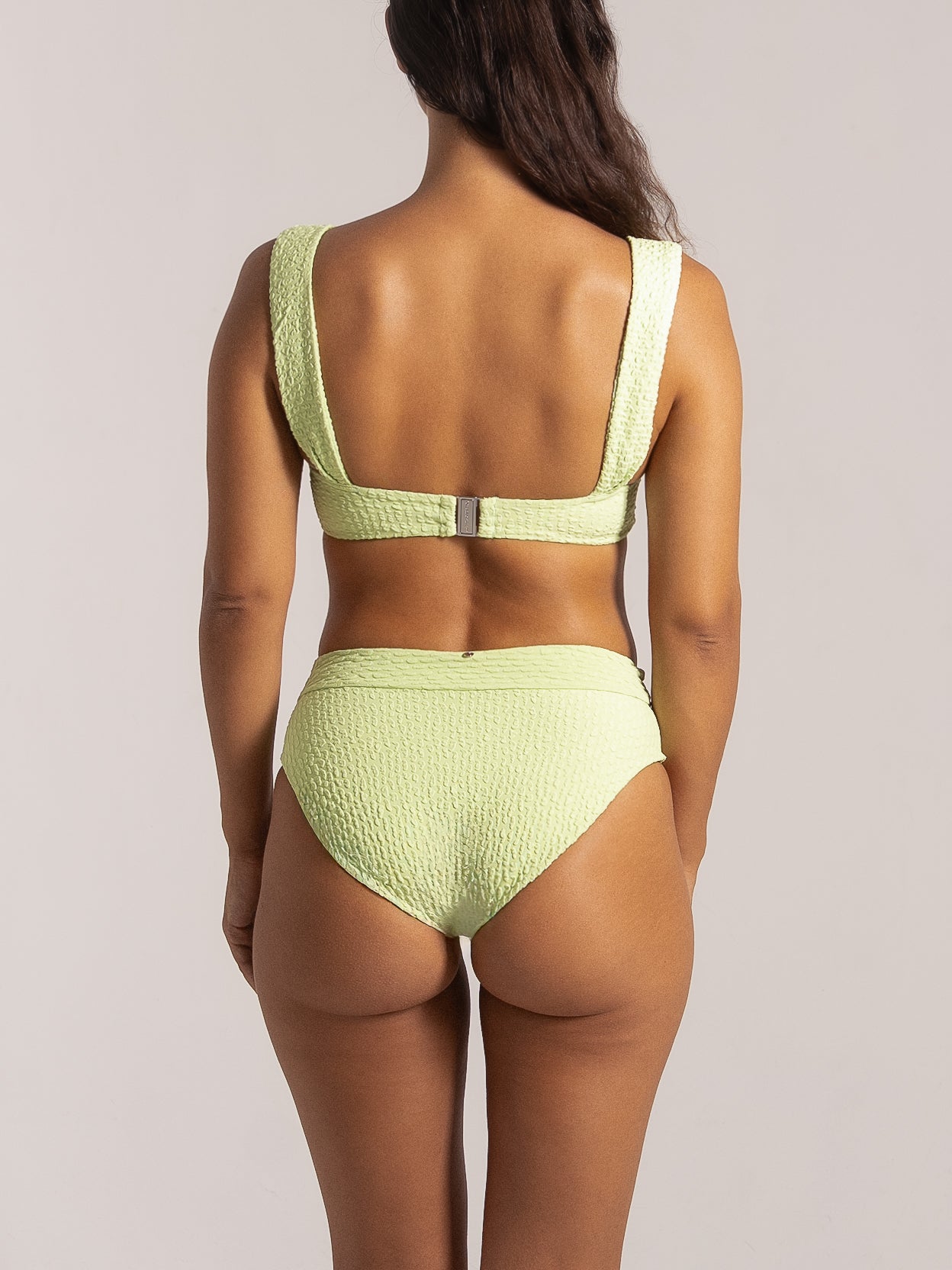 Back view of a lime green high-waisted bikini bottom with textured fabric.