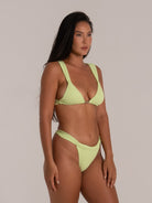 Woman wearing lime green plunge bikini top with wide straps, shown from a side angle.