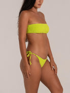 Side pose of model in a lime green bandeau bikini set with a bold textured finish