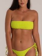 Front view of a woman wearing a lime green bandeau bikini set with a textured finish and tie-side bottoms, showcasing a bold summer look with a sculpted fit.