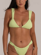 Close-up front view of a lime green textured bikini with wide shoulder straps and a central gold metal detail.