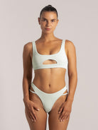 Model wearing a mint green cutout bikini top with a scoop neck and wide shoulder straps