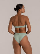 Woman wearing a mint green bandeau bikini with back clasp and high-waisted bottom, showing rear view.