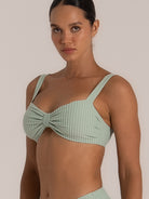 Angled close-up of mint green bikini top with center bow and supportive structure