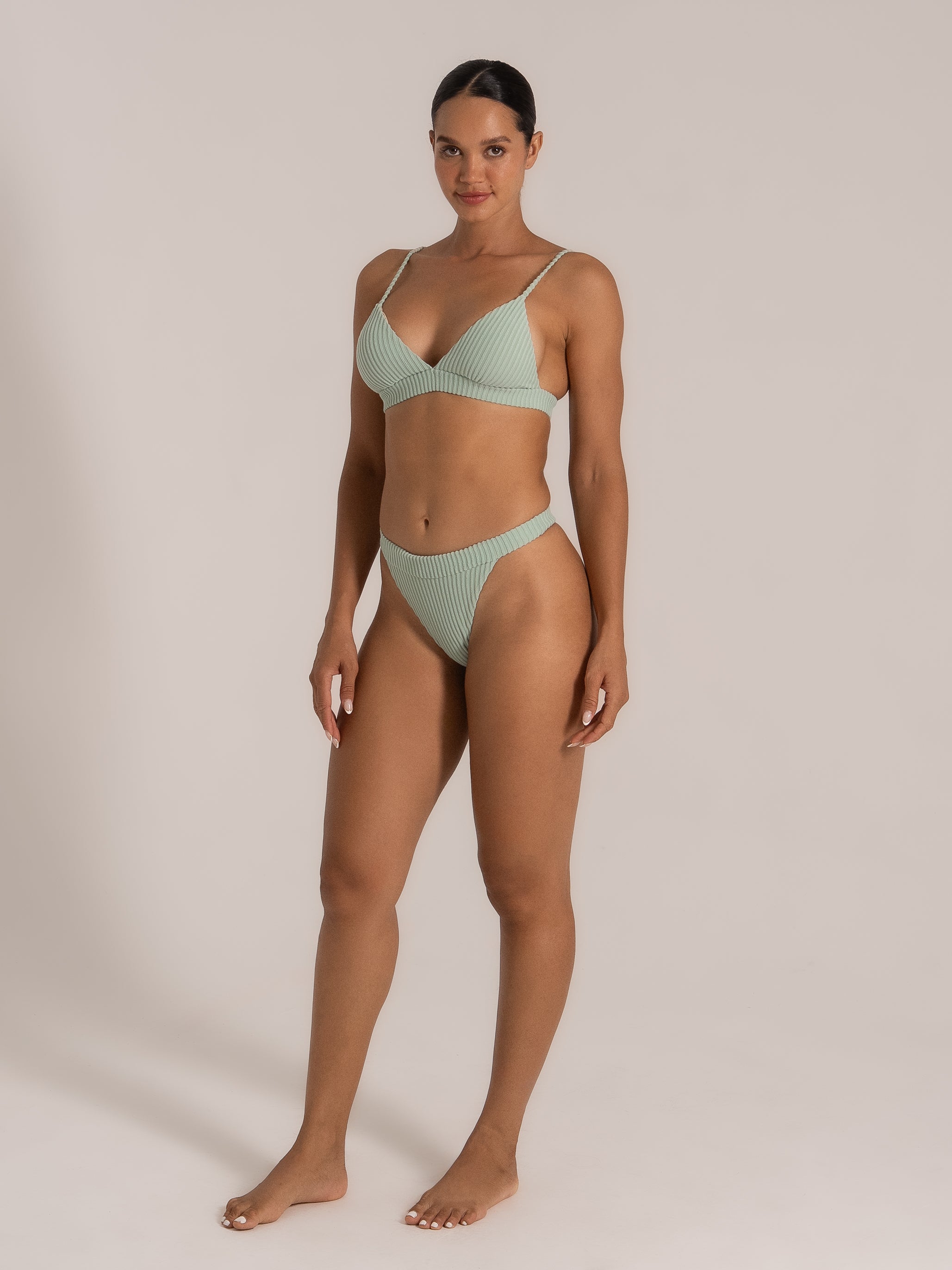 Side angle of a model in mint green bikini with deep V neckline and ribbed texture.