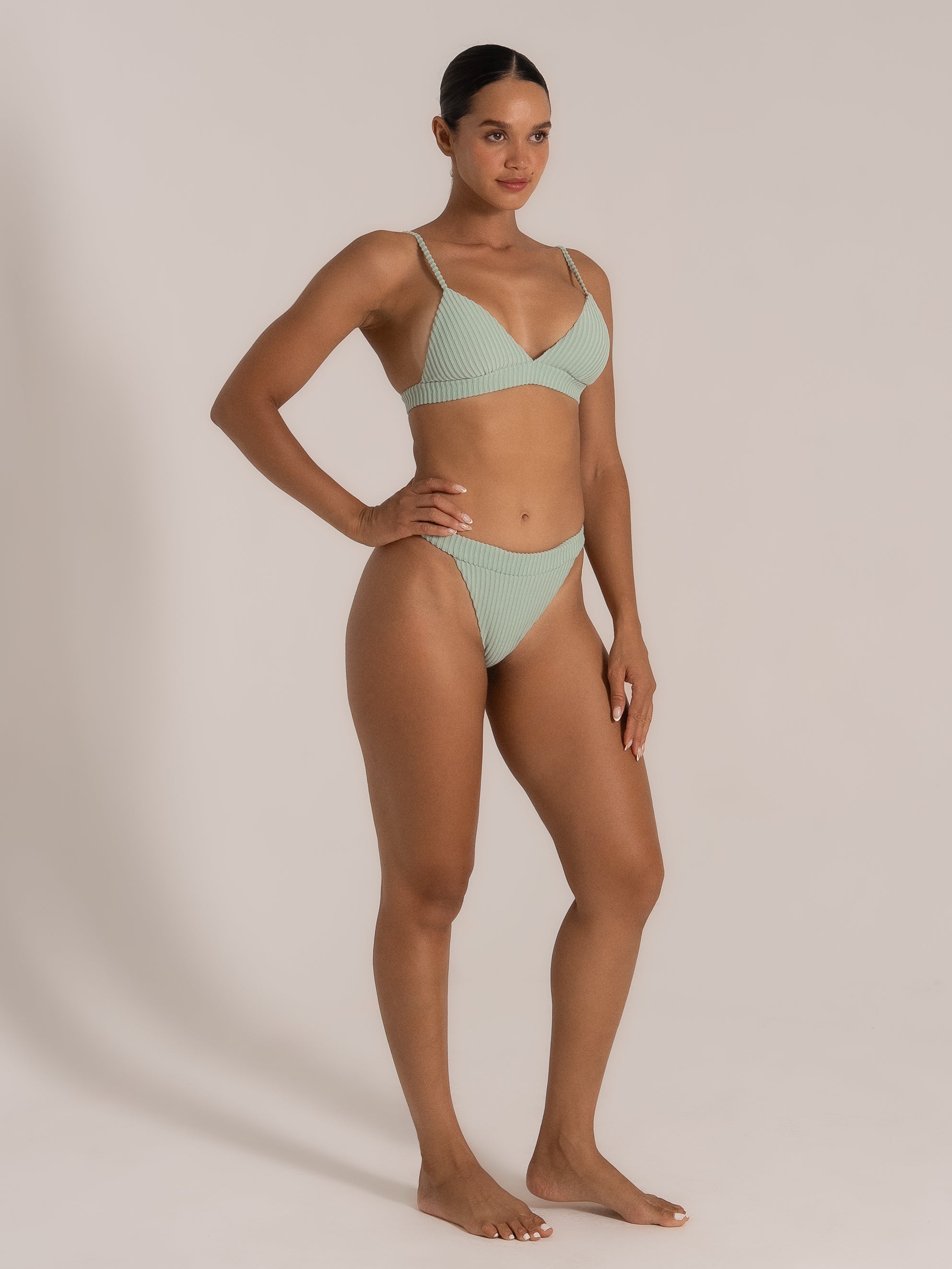 Stylish mint green high-leg bikini set with braided straps and wide waistband, side angle view.