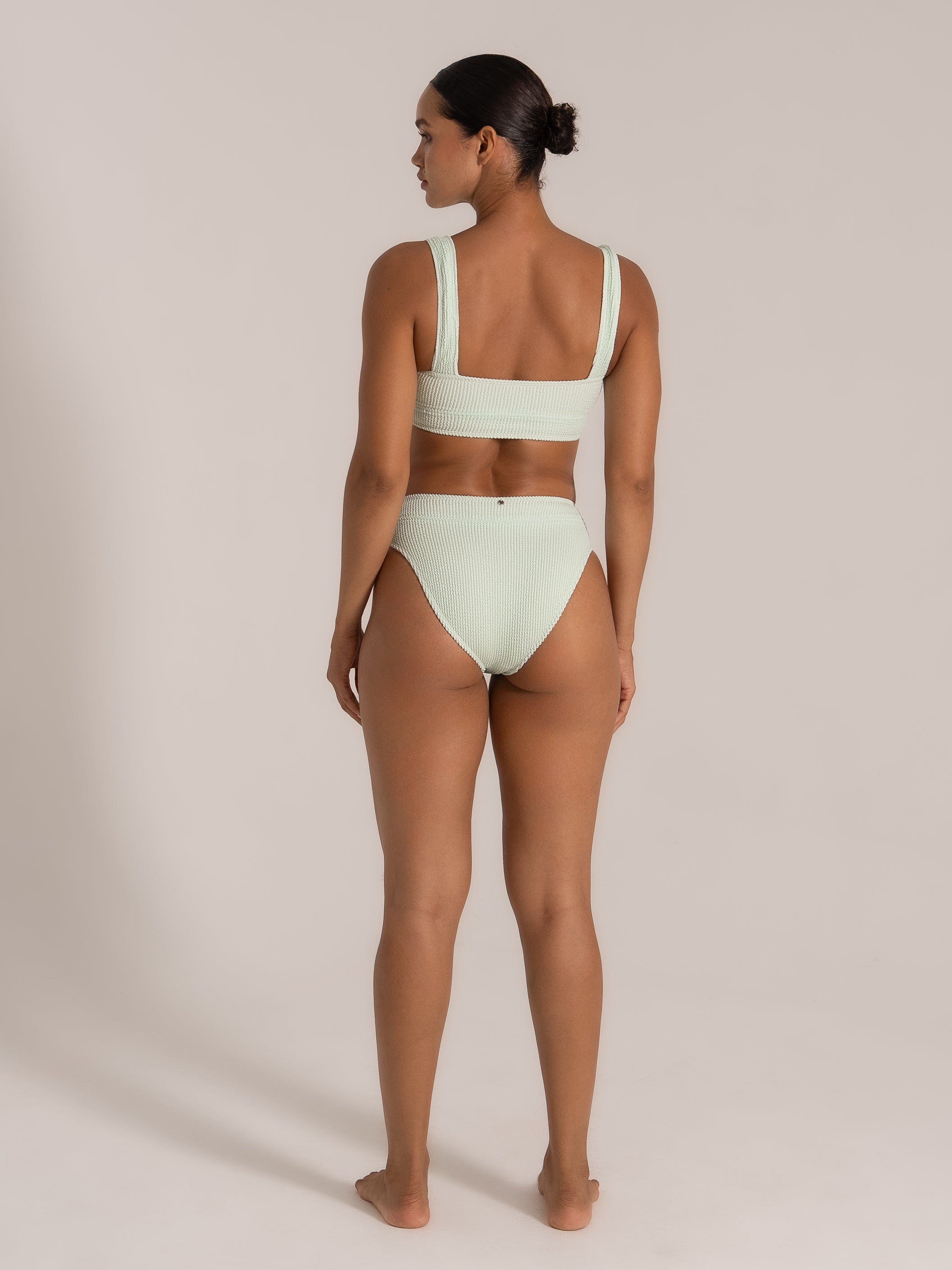 Back view of woman wearing mint green high-waist bikini set with wide straps