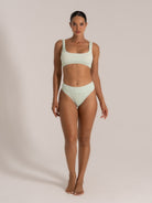 Front view of model in mint green high-waisted bikini with scoop top