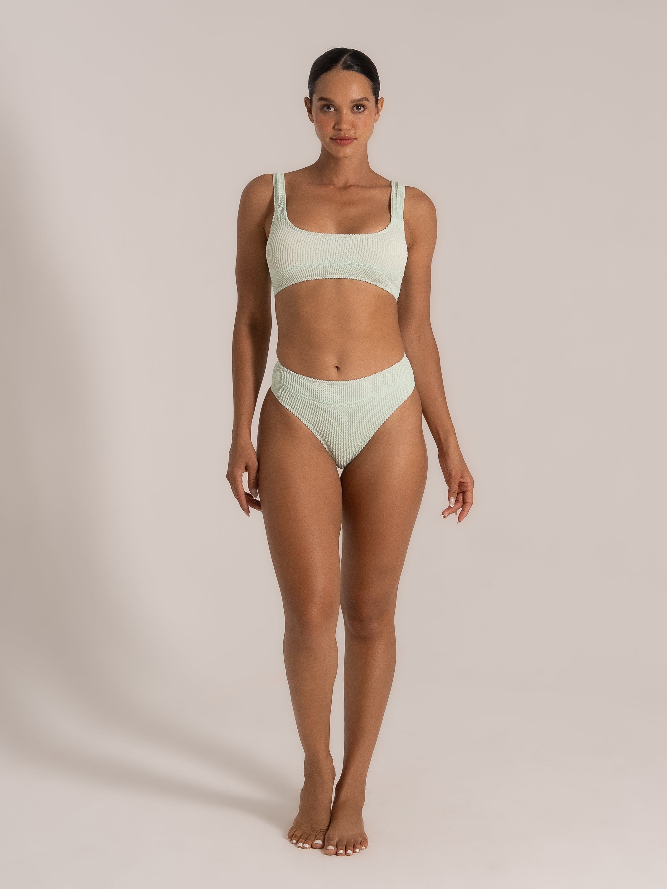 Front view of model in mint green high-waisted bikini with scoop top