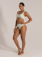 Side view of woman in mint green bikini set featuring wide shoulder straps and ribbed fabric