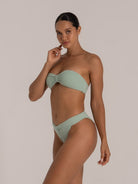 Side profile of model in ribbed mint green bandeau bikini set with flattering twist detail.