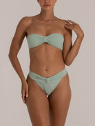 Woman wearing a mint green textured bandeau bikini set with a twisted front and high-waisted bottom, front view.