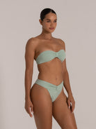 Woman in mint green textured strapless bandeau bikini with twist front and high-leg bottoms.