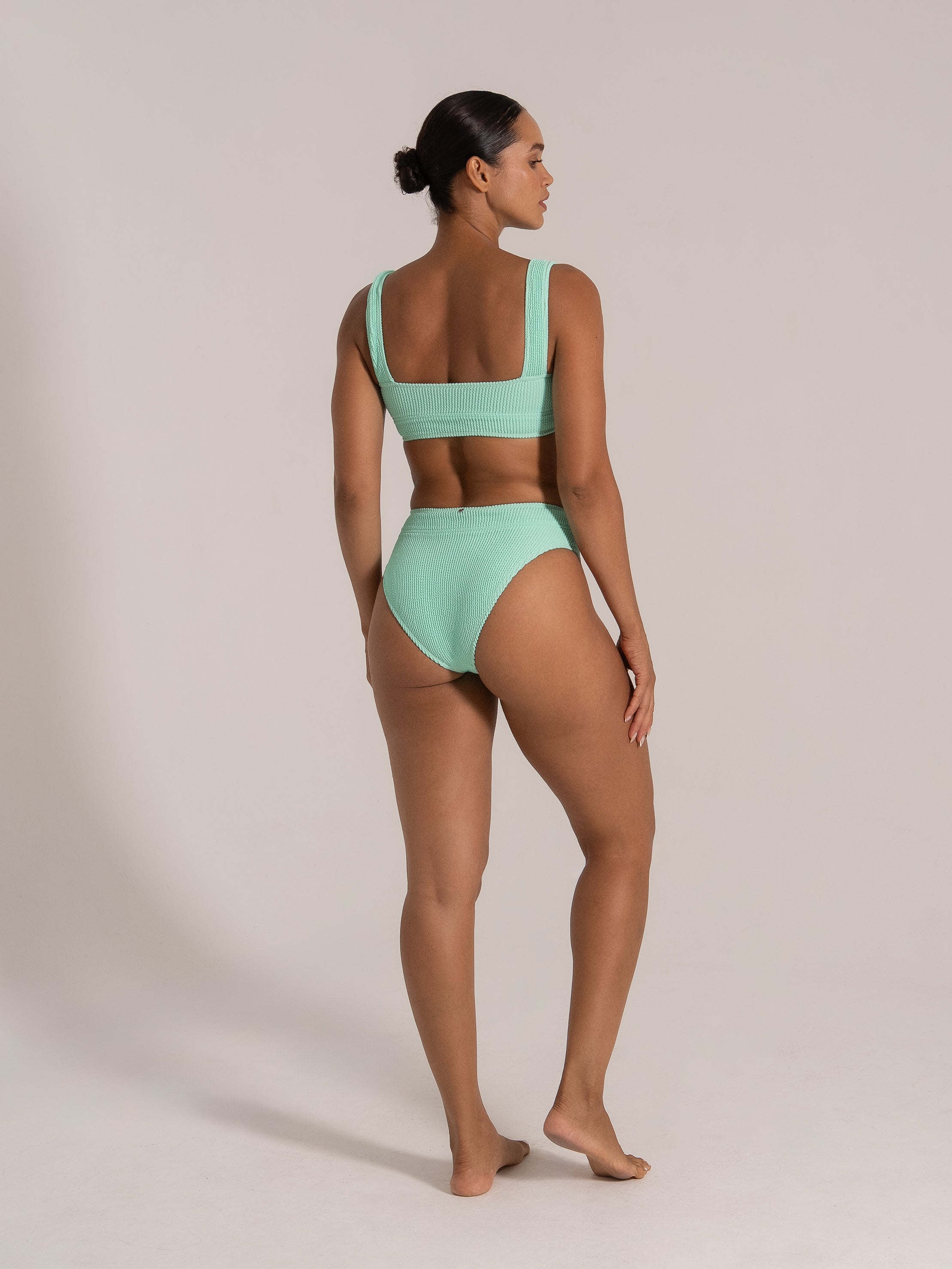 Angled back view of a mint green textured bikini with scoop back and supportive top.