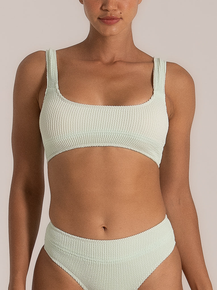 Front view of a woman wearing a mint green textured bikini set with a square neckline top and high-waisted bottoms, both featuring a waffle-knit fabric for added structure and comfort.