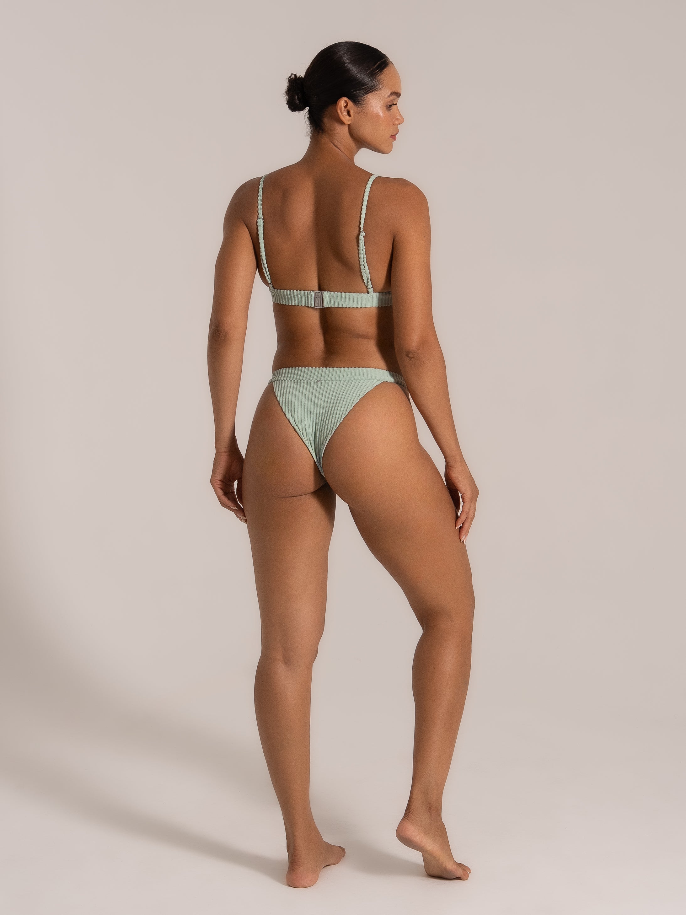 Angled back view of a mint green bikini showing braided shoulder straps and secure clasp.