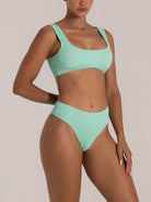 Woman wearing mint green textured high-waisted bikini set with thick straps, front view