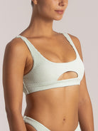 Side view of a mint green cutout bikini top with wide straps and textured fabric