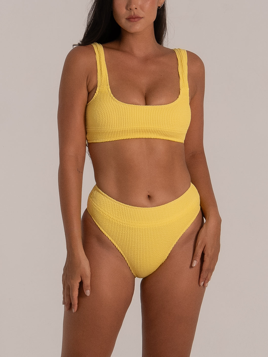 Angled view of high-rise mustard yellow bikini bottom with body-hugging fabric